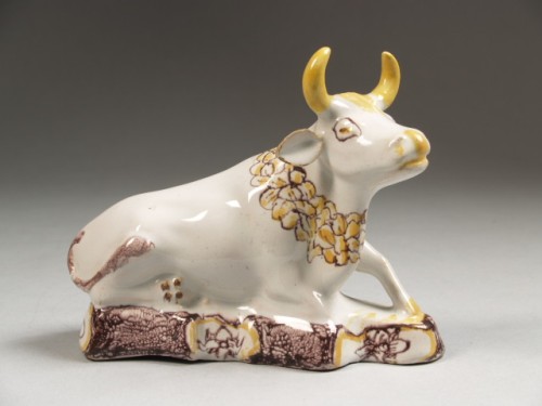 Plastiek in de vorm van een liggende koe met gele en paarse beschildering