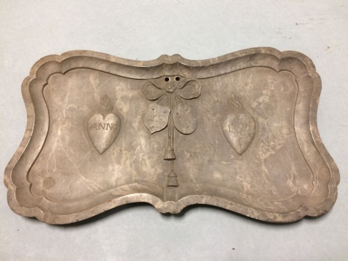 Langwerpige plaquette met opstaande accolade-randen met opschrift ANNO 1773