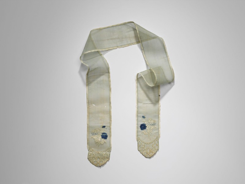 Smalle sjaal van lichtblauwe batist met aan de uiteinden versieringen