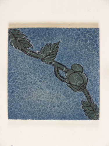Tegel met een groen floraal en diagonaal ornamentdecor op een blauw gesprenkeld fond