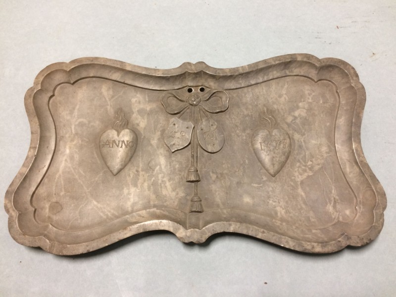 Langwerpige plaquette met opstaande accolade-randen met opschrift ANNO 1773