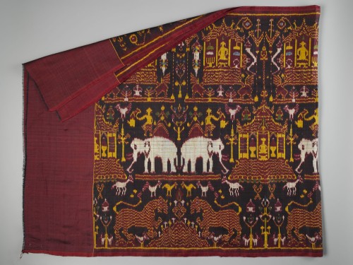 Doek van rode en zwart zijde met ikat inslag, met pagodes, olifanten, leeuwen en bomen