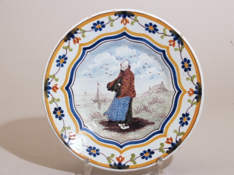 Bord met polychroom decor Katwijk voorstellende een vissersvrouw aan zee
